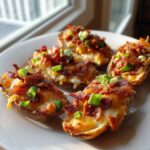 Four crispy potato skins loaded with melted cheese, bacon bits, and fresh green onions.