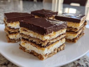 Four square slices of layered chocolate eclair cake featuring graham crackers, cream filling, and a thick chocolate topping.