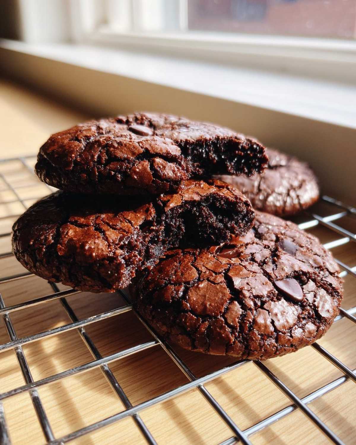 Close-up of fudgy chocolate brownie cookies with cracked tops cooling on a wire rack.