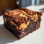 A close-up of a fudgy peanut butter swirl brownies square showing the crackly top and creamy swirl.