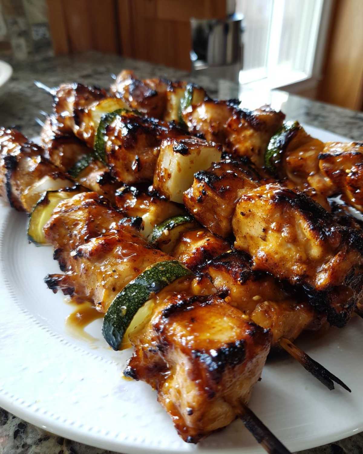 Close-up of several grilled honey garlic chicken skewers with zucchini pieces, glistening with glaze.