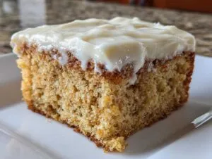 Close-up of a moist slice of spice cake topped generously with thick, white cream cheese frosting.