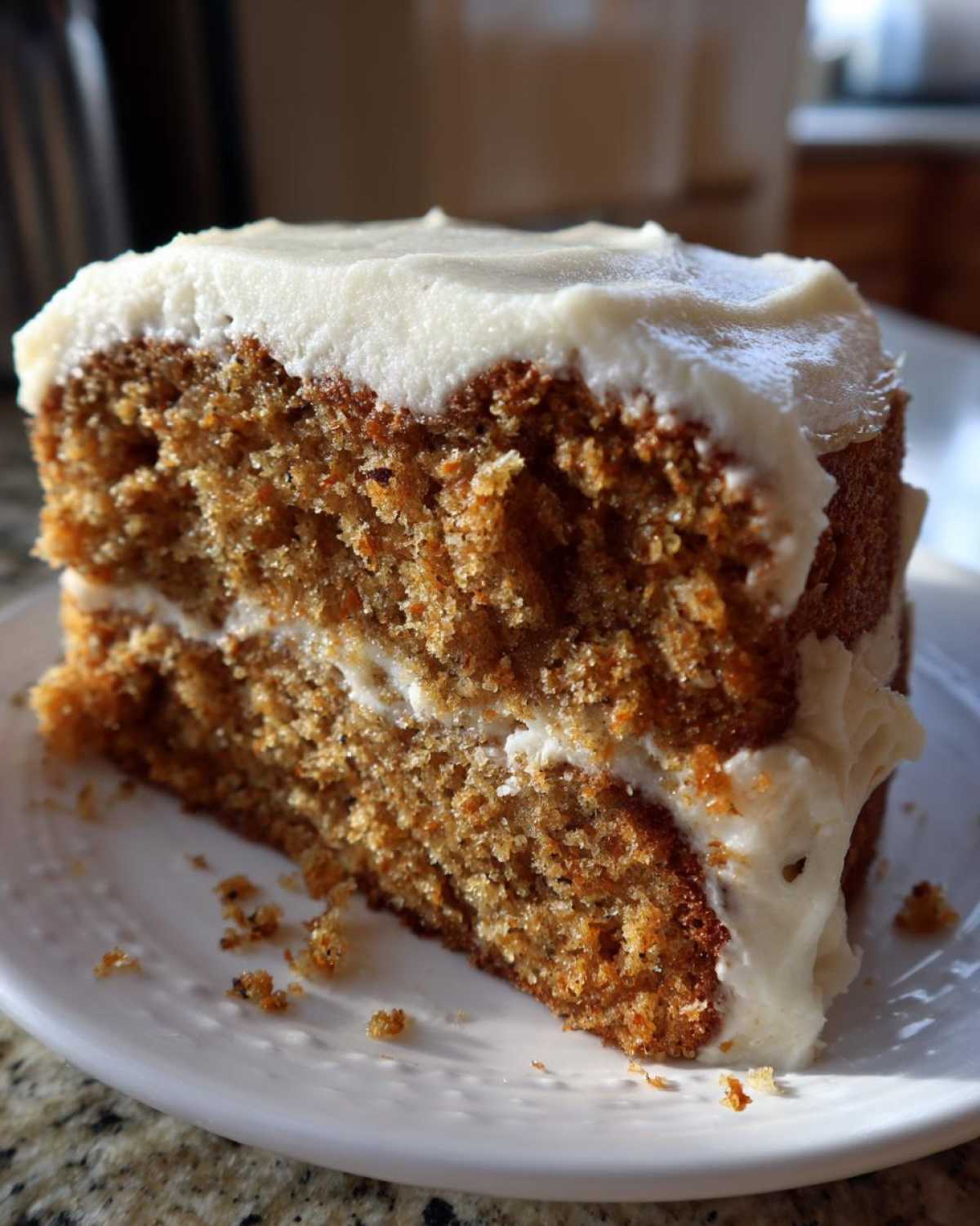 Close-up of a moist slice of two-layer spice cake topped and filled with thick white cream cheese frosting.
