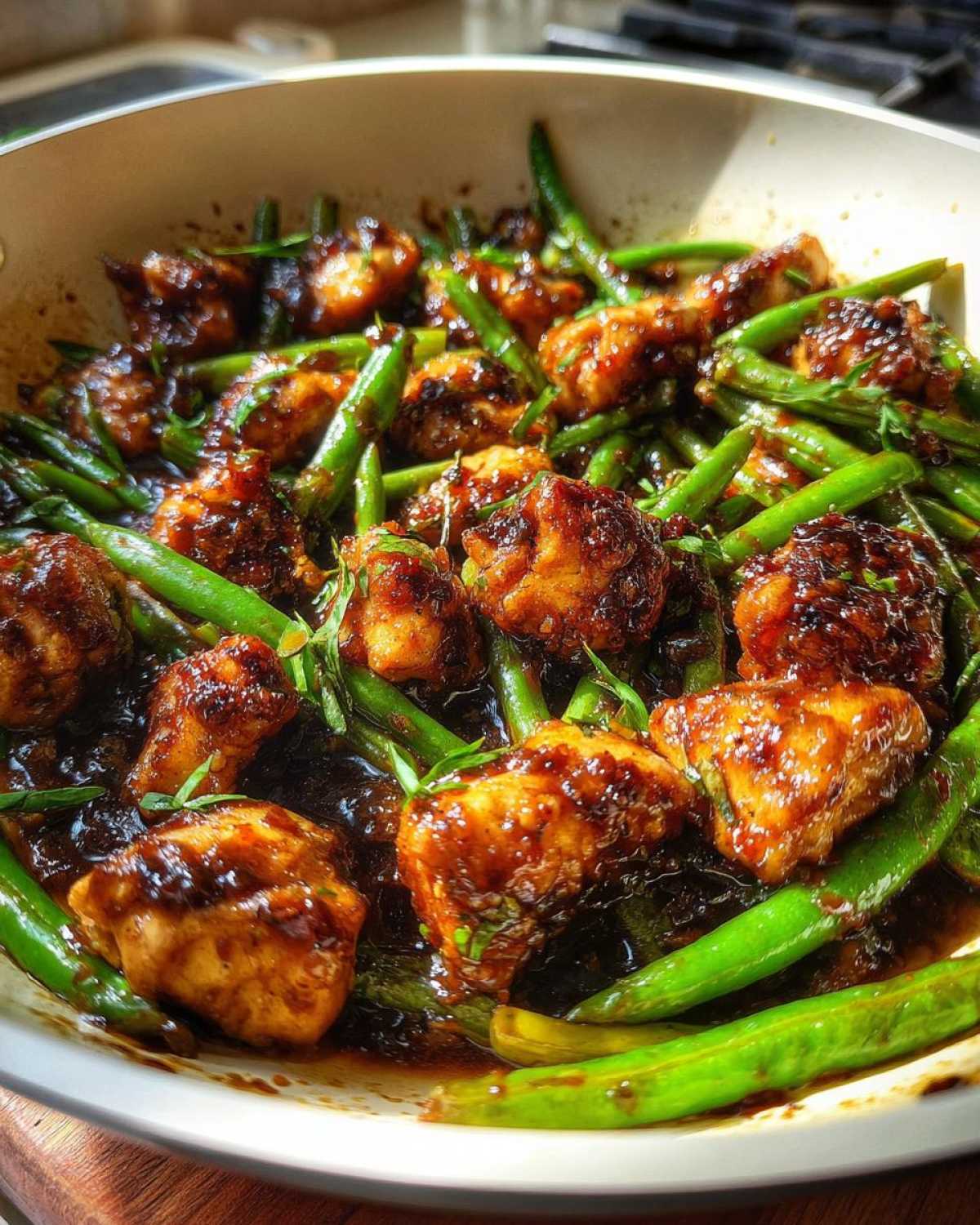Close-up of glazed chicken pieces mixed with bright green beans in a dark sauce, representing a 1-pan chicken and green beans dinner.