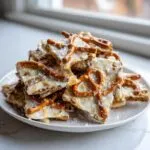 A pile of broken pieces of peanut butter pretzel bark topped with white chocolate and sea salt.