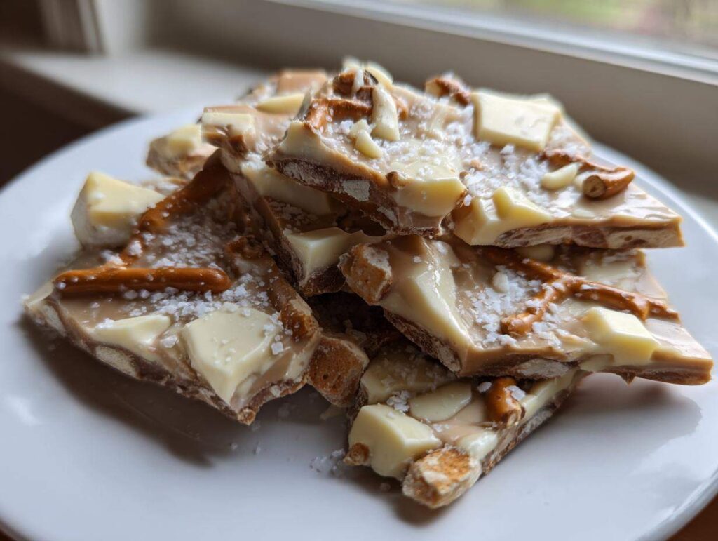 Close-up of broken pieces of peanut butter pretzel bark topped with white chocolate chunks and sea salt.