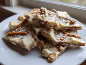 Close-up of broken pieces of peanut butter pretzel bark topped with white chocolate chunks and sea salt.