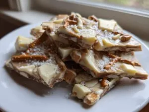 Close-up of broken pieces of peanut butter pretzel bark topped with white chocolate chunks and sea salt.