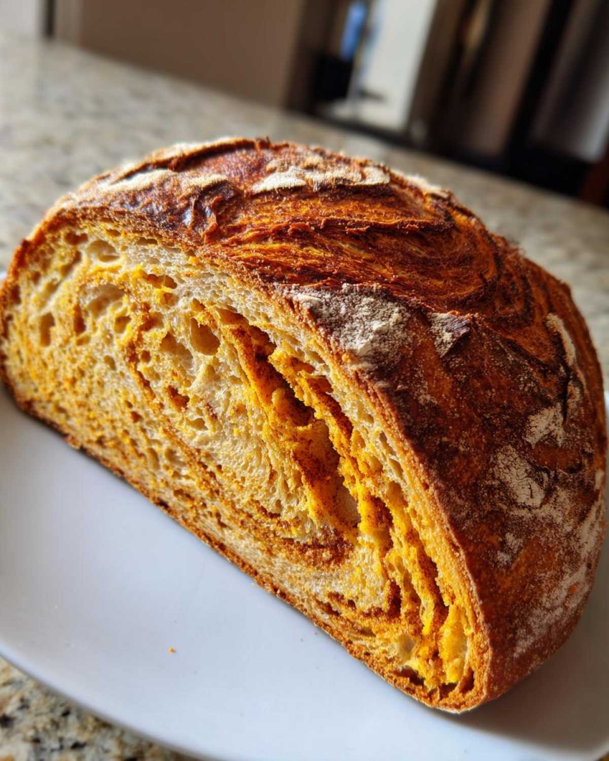 Close-up of a sliced pumpkin sourdough loaf showing the vibrant orange swirl and open crumb structure.