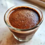 Close-up of rich, airy chocolate mousse served in a small, clear glass.