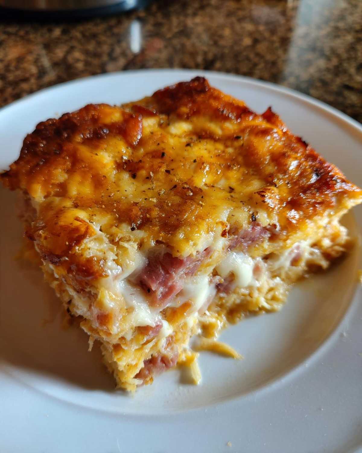 Close-up of a cheesy, golden-brown slice of homemade reuben bake showing layers of corned beef and melted Swiss cheese.