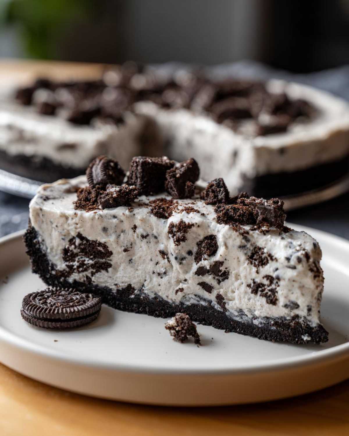 A generous slice of creamy, no-bake oreo pie with a dark chocolate crust, topped with cookie chunks.