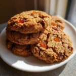 A close-up stack of three golden brown fruitcake cookies, studded with visible pieces of candied fruit.