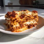 A thick, perfectly layered slice of ultimate comfort lasagna with rich meat sauce and melted cheese.
