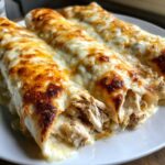 Three baked white chicken enchiladas smothered in melted, bubbly, and browned cheese sauce.