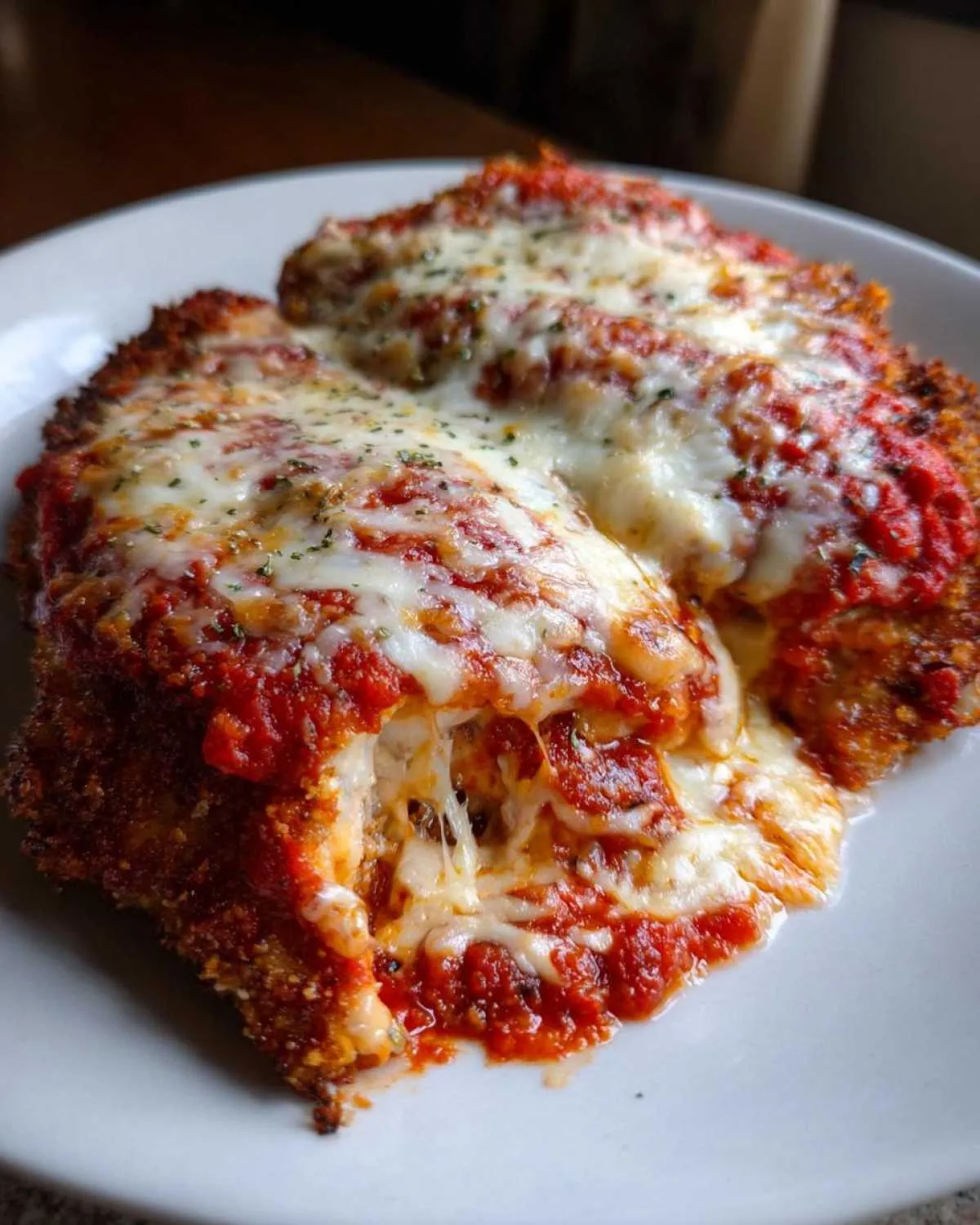 Close-up of two servings of amazing chicken parmesan recipe covered in melted mozzarella and marinara sauce.