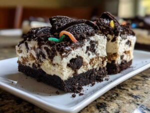 Two slices of amazing dirt cake featuring a thick Oreo crust, creamy filling, and gummy worms on top.