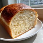 Close-up of a slice of fluffy, homemade bread showing a soft interior and golden-brown crust, perfect for a low-calorie bread recipe.