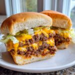 Close-up of two halves of big mac sloppy joes featuring double meat, melted cheese, lettuce, pickles, and onions on soft buns.