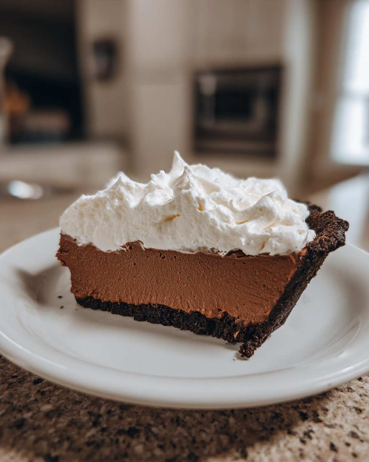 A perfect slice of chocolate cream pie with a dark crust, rich filling, and fluffy whipped cream topping.