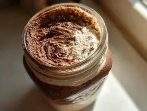 Overhead close-up of rich chocolate swirl chia pudding topped with cream in a glass mason jar.