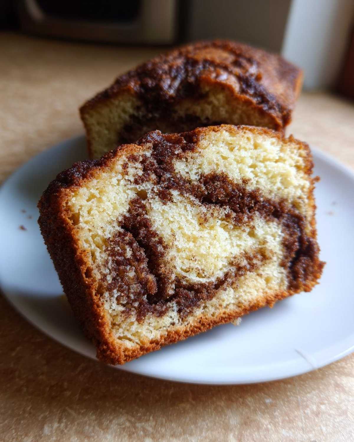 Close-up of a moist slice of cinnamon bread showing a rich swirl of dark cinnamon filling inside the light cake.