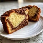 Two slices of moist cinnamon bread showing a beautiful swirl of cinnamon filling inside on a white plate.