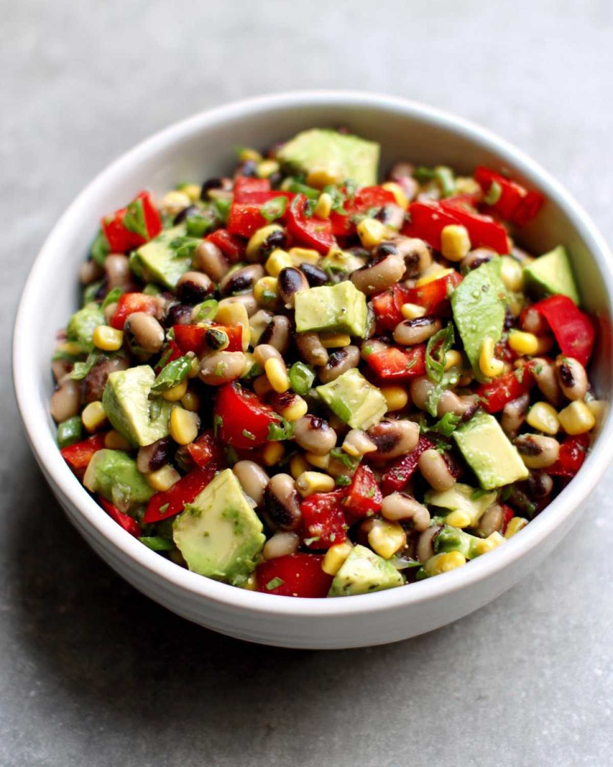 Close-up of a vibrant cowboy caviar recipe featuring black-eyed peas, corn, avocado, and red peppers.