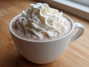 Close-up of a mug filled with creamy white hot chocolate topped generously with whipped cream.