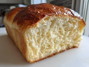 Close-up of a freshly baked japanese milk bread loaf showing its incredibly soft, stringy crumb texture.