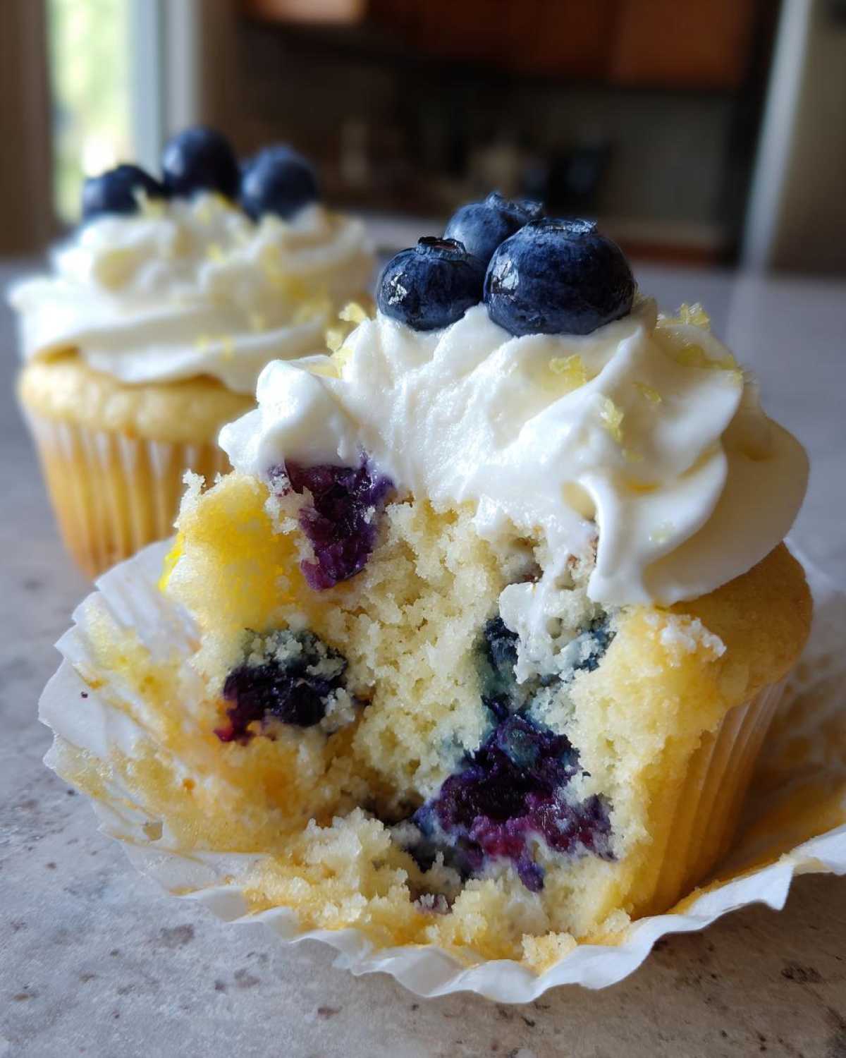 Close-up of a fluffy lemon blueberry cupcakes cut in half showing moist crumb and blueberries.