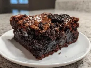 A close-up of a rich, fudgy square of oreo brownies topped with crushed cookie pieces.