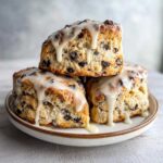 Three delicious chocolate chip scones stacked and drizzled with thick white glaze.