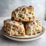 Three delicious chocolate chip scones stacked and drizzled with thick white glaze.