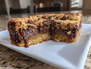 Close-up of a thick, gooey chocolate chip cookie bar showing melted chocolate oozing out.