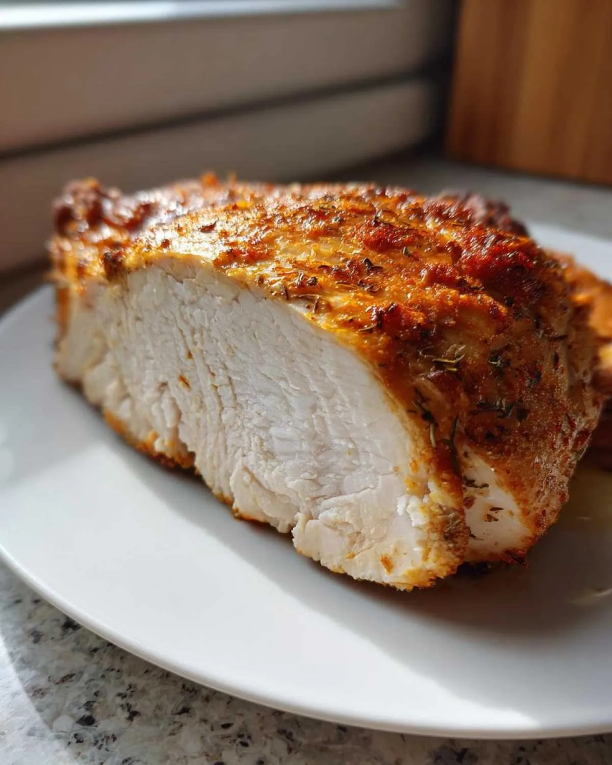 Close-up of a perfectly cooked, juicy air fryer chicken breast, showing the white interior and seasoned crust.