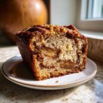 Close-up of a moist slice of amazing apple bread showing cinnamon swirl and baked apple chunks.