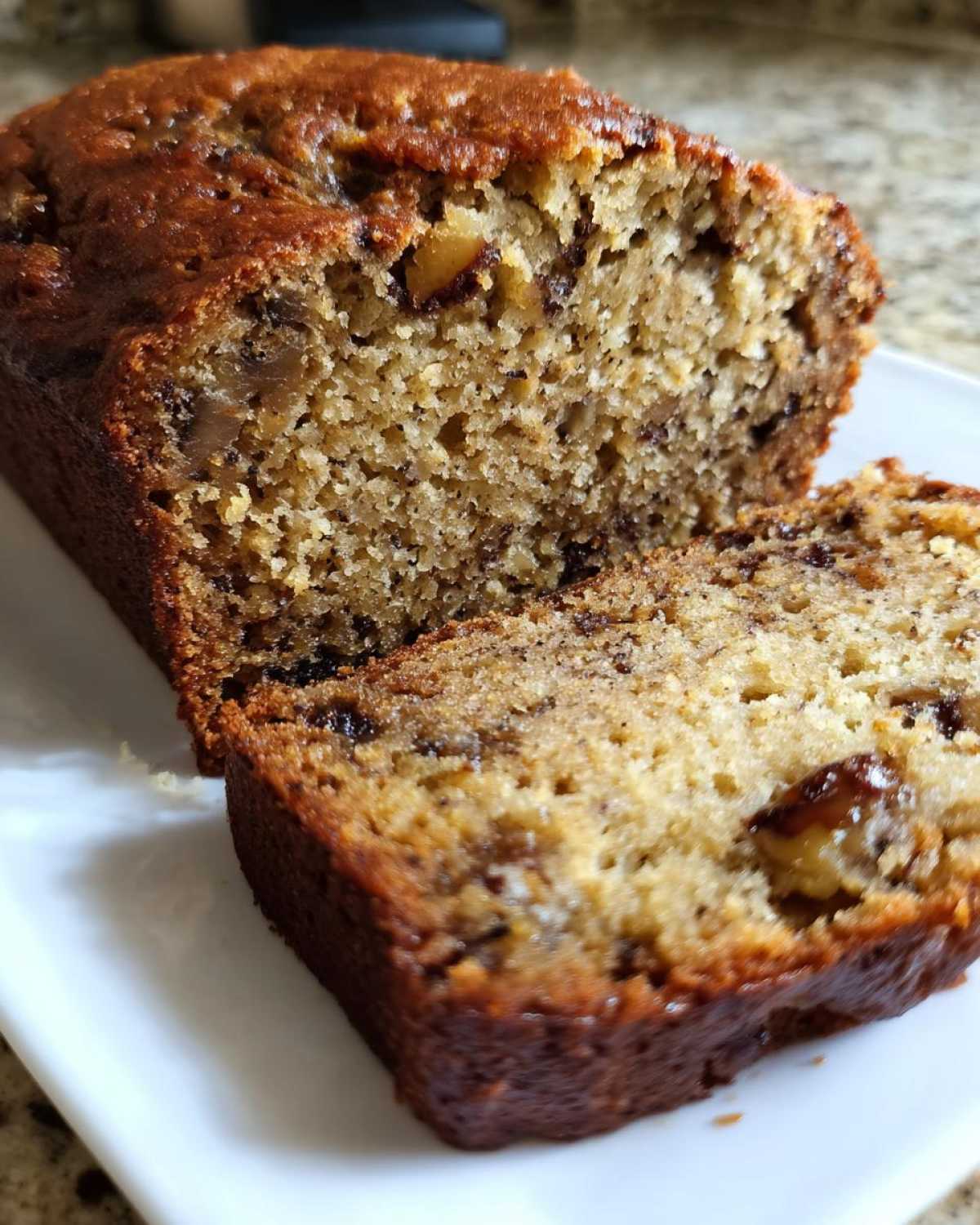 Close-up of a moist slice of greek yogurt banana bread showing nuts and chocolate chips.