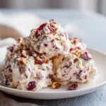 Close-up of scoops of creamy cranberry salad mixed with dried cranberries and topped with chopped pecans.
