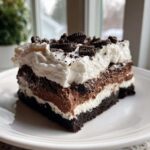 A generous slice of layered chocolate lasagna with a cookie crust, cream cheese, chocolate mousse, and whipped topping.