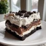 A generous slice of layered chocolate lasagna with a cookie crust, cream cheese, chocolate mousse, and whipped topping.