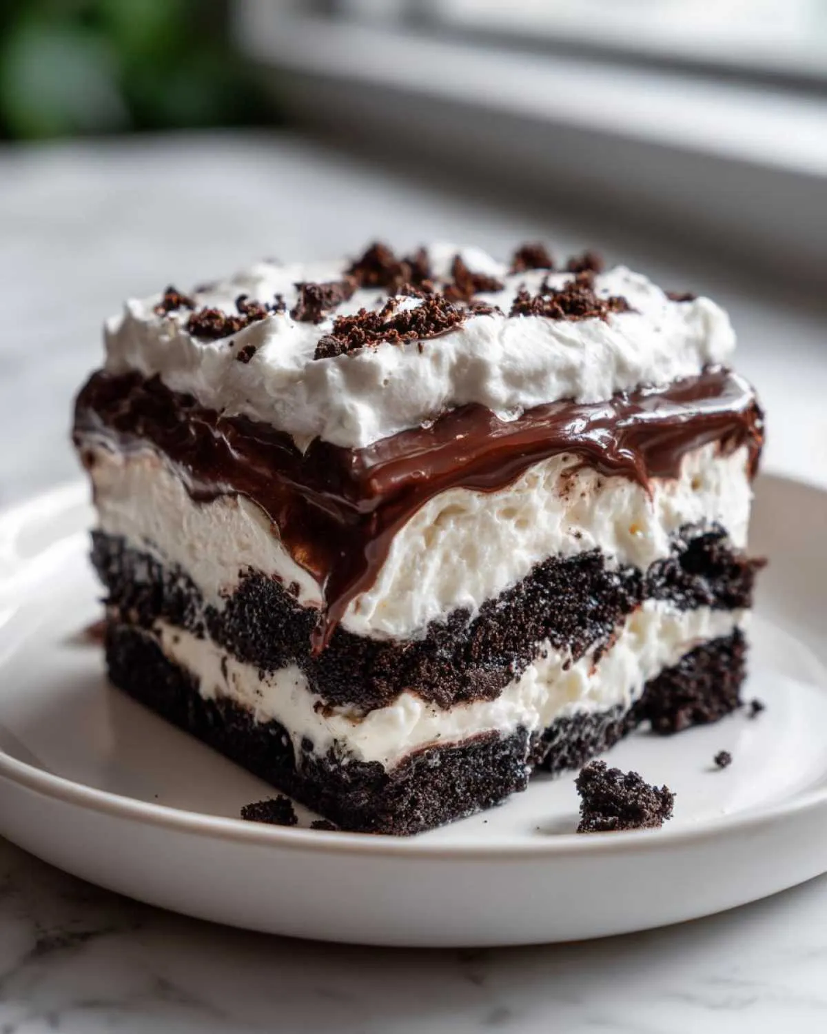 A rich, layered slice of chocolate lasagna featuring dark crust, white cream filling, and chocolate topping.