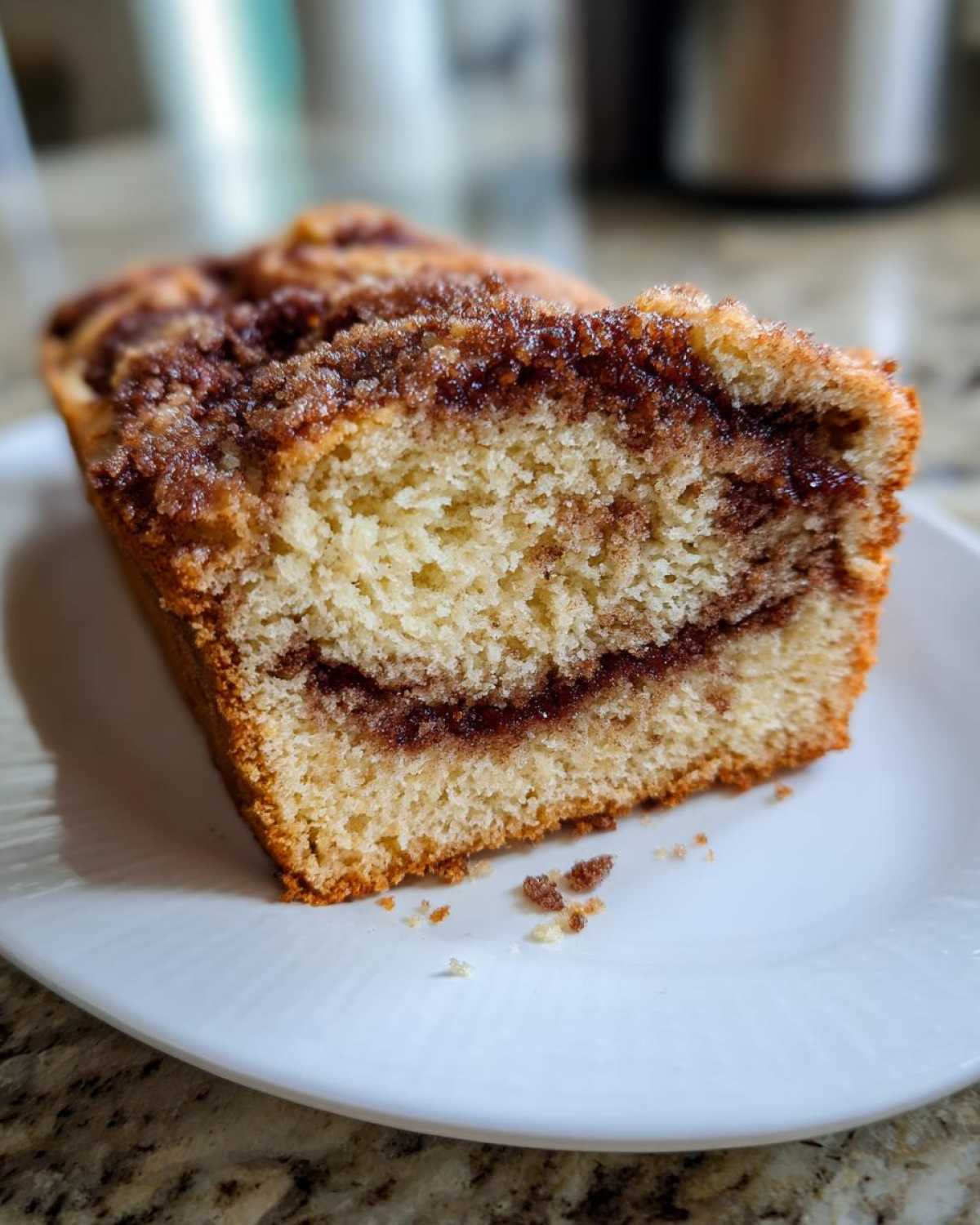 Close-up of a thick slice of moist cinnamon bread showing the interior crumb and dark cinnamon swirl.