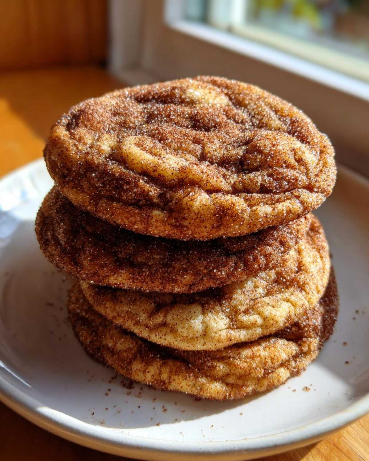 A stack of three soft and chewy cinnamon cookies generously coated in cinnamon sugar.