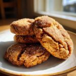 A stack of four soft, chewy cinnamon cookies heavily coated in sparkling sugar, resting on a light plate.