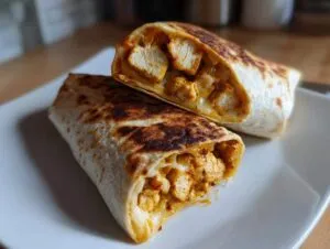 Two halves of a grilled air fryer chicken mozzarella wrap showing seasoned chicken chunks and melted cheese filling.