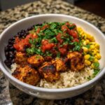 Close-up of a delicious chicken burrito bowl featuring seasoned chicken, rice, black beans, corn, and fresh salsa.