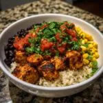 Close-up of a delicious chicken burrito bowl featuring seasoned chicken, rice, black beans, corn, and fresh salsa.