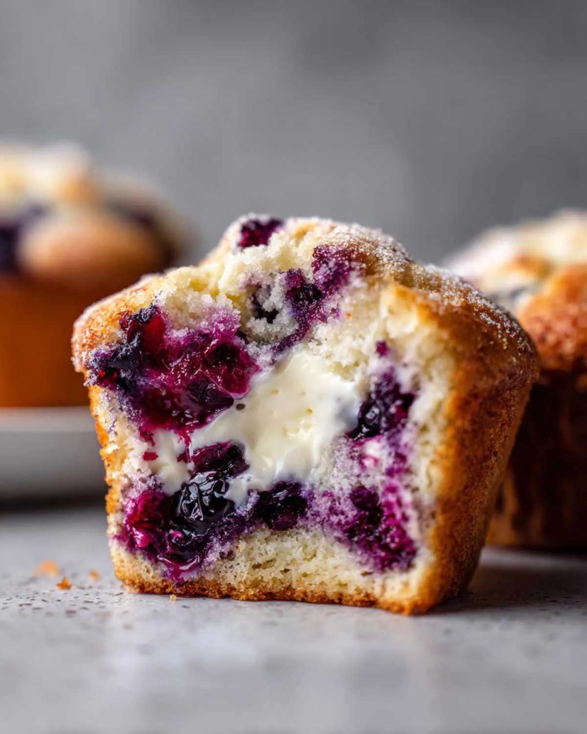 Close-up of a blueberry cream cheese muffin cut in half showing the gooey cream cheese center and burst blueberries.