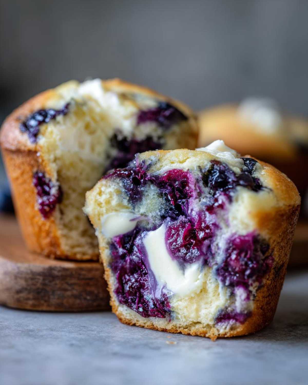 Close-up of a blueberry cream cheese muffin cut in half, showing the moist interior with bursting blueberries and a cream cheese center.
